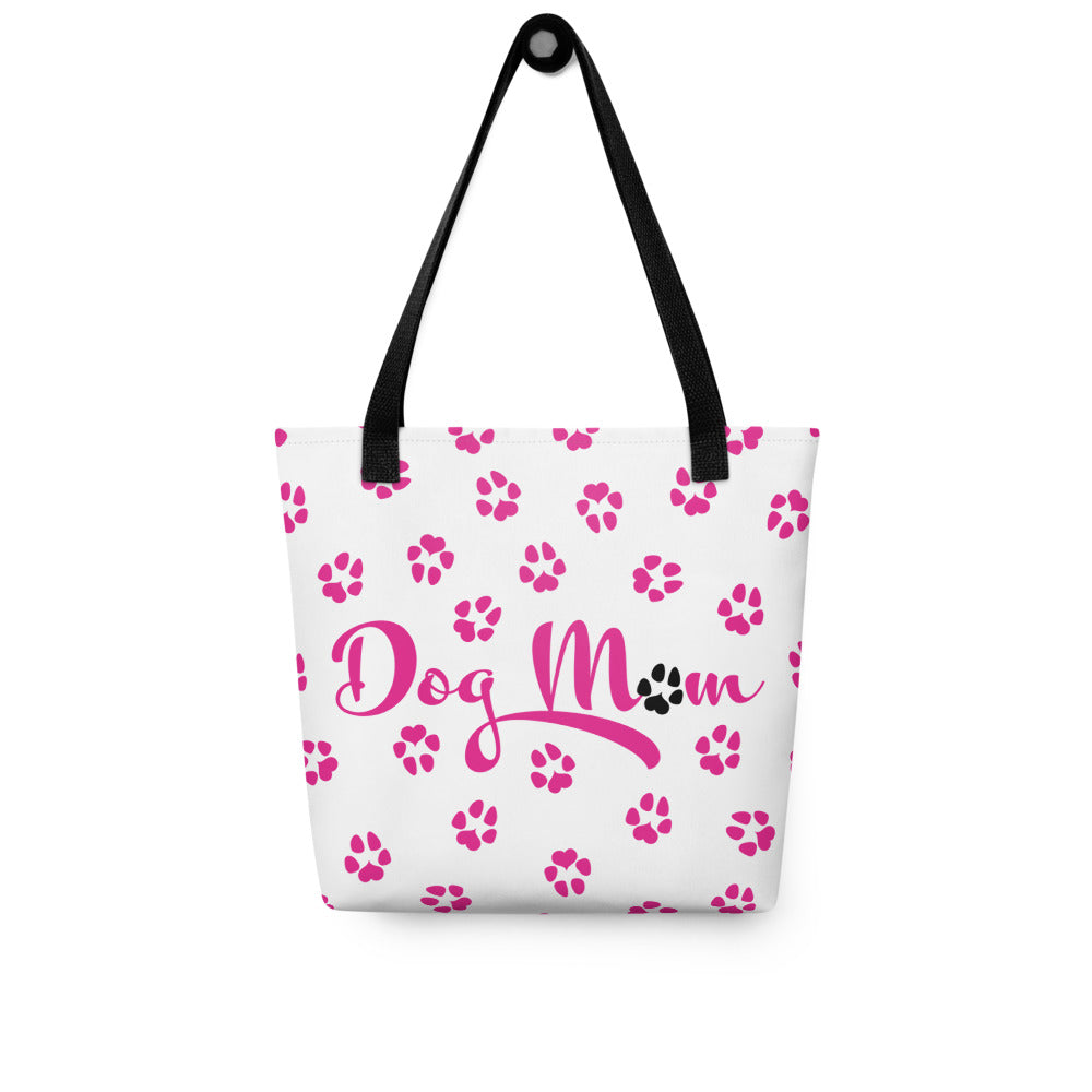 Tote bag with white background and black handle. Dog Mom is written on the front with dog paw prints all over in pink with one black paw in Mom.