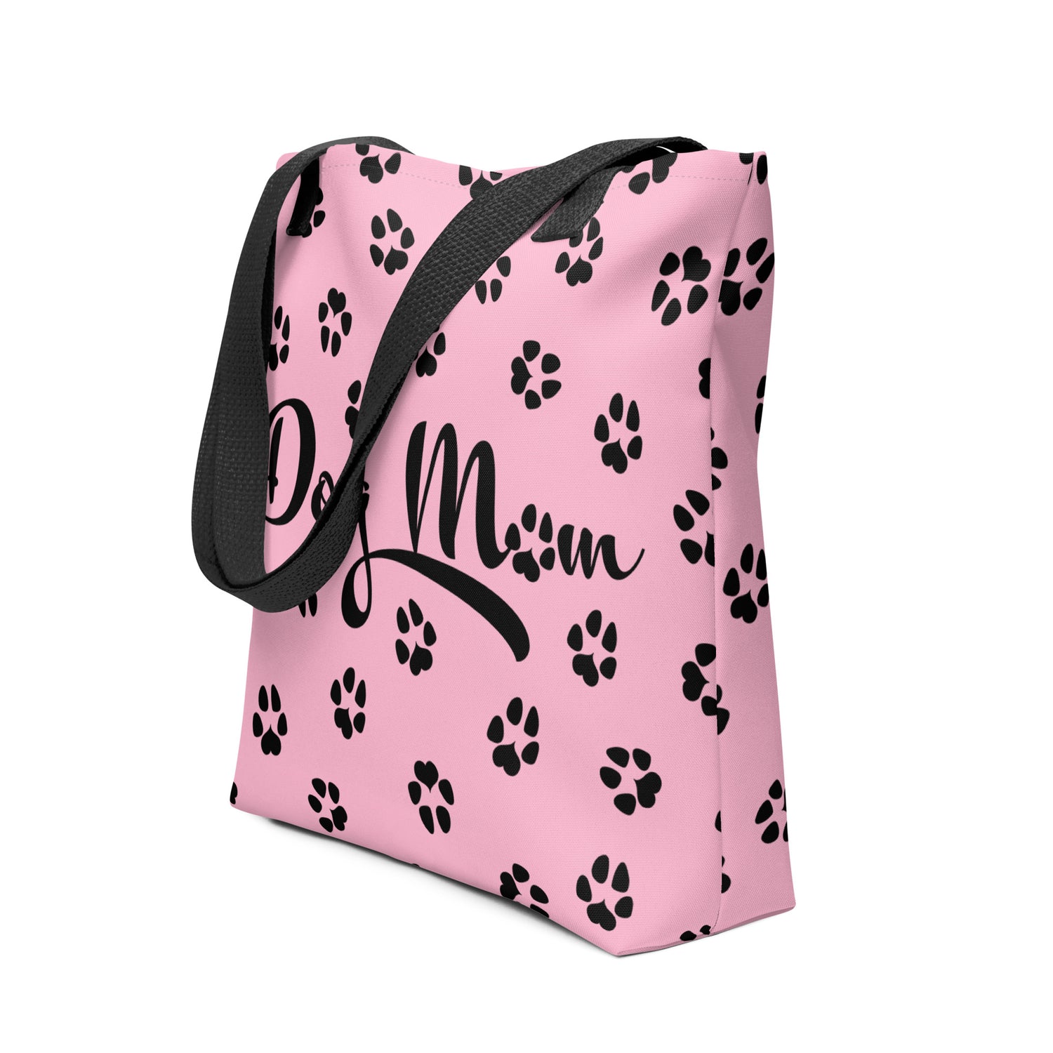 Tote bag with pink background. Dog Mom is written on the front with dog paw prints all over in black. The handle is black